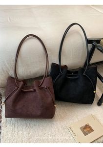 Close-up of suede tote bags with drawstring closure and golden metal sphere accents