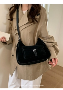 Close-up of minimalist black suede tote bag with front pocket and retro buckle detail