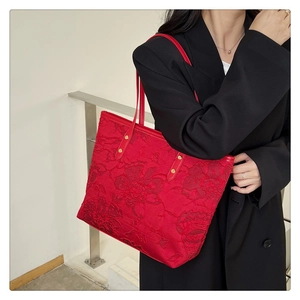 Detail of red bridal tote bag with intricate floral embroidery and satin finish