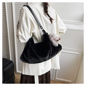 Detail of plush black faux fur shoulder bag with leather strap and cute lamb charm