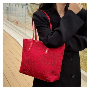 Detailed view of red floral jacquard tote bag with leather handles and gold studs