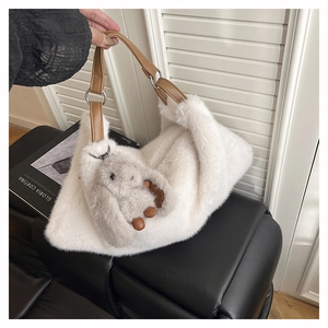 Dettaglio borsa a spalla in peluche bianca con manici in pelle e ciondolo a coniglio