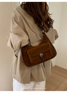 Brown suede tote bag with silver buckle flap pocket shown in a minimalist retro style