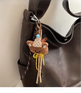 Gros plan d'un pendentif ours en peluche marron avec chapeau de fête sur un grand sac