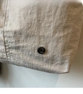 Détail du tissu en nylon beige imperméable avec coutures soignées et logo noir décoratif