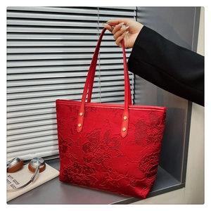 Detail of red floral jacquard tote bag with leather handles and gold rivet accents