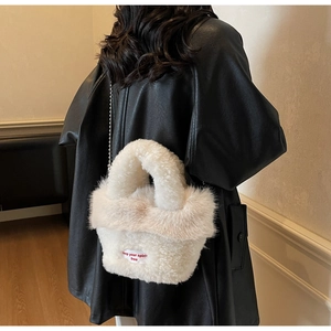 Détail du sac à main en peluche blanc avec chaîne argentée porté sur une veste en cuir noir