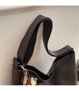 Gros plan du sac hobo marron foncé avec large bandoulière et détail de nœud tressé