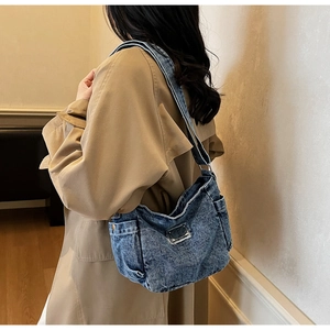 Détail du sac cabas en denim bleu montrant la texture délavée et la plaque en métal