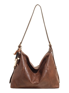Brown vintage faux leather tote bag with long strap and bohemian bead charm on white base