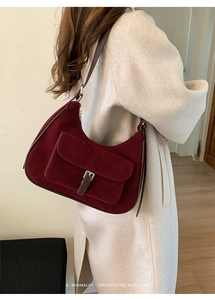 Detail of burgundy suede shoulder bag featuring a vintage silver buckle and leather strap
