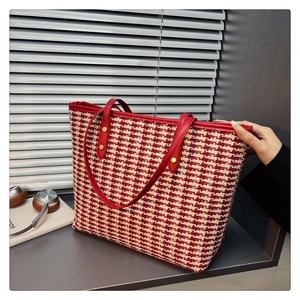 Detail of red houndstooth tote bag with leather handles and gold metal rivets
