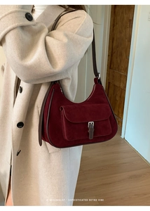 Detail of wine red suede shoulder bag featuring retro strap and front pocket texture