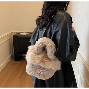 Détail du sac à main en fausse fourrure abricot avec chaîne en métal et étiquette tissée