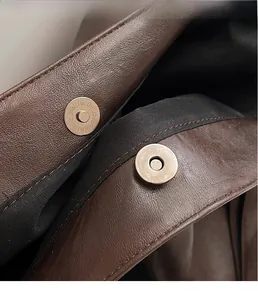 Détail des fermoirs magnétiques en métal sur un sac cabas en cuir grainé marron