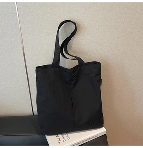 Détail du grand sac cabas en nylon noir montrant les doubles anses et la boucle métallique