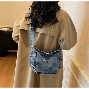 Detailed view of the vintage washed denim crossbody bag featuring industrial style pockets