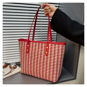 Detail of red and cream houndstooth woven tote with leather straps and gold metal studs