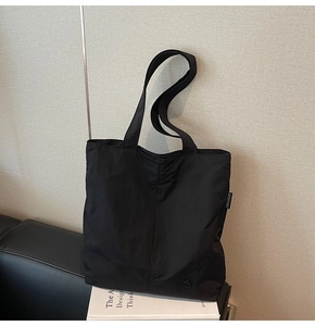 Détail du sac cabas noir en nylon imperméable avec étiquette de marque et logo métallique