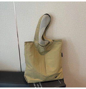 Détail du sac fourre-tout vert moutarde avec longues anses et détail en métal argenté