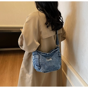 Side view of washed blue denim tote bag with functional small pocket and metal hardware