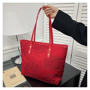 Detail of red floral lace tote bag featuring elegant golden rivets and silk texture