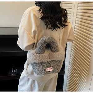 Détail d'un sac en fausse fourrure grise avec étiquette Keep Your Spirit Free et chaîne