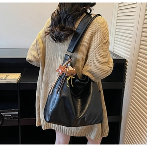 Détail d'un grand sac seau vintage noir avec breloques d'ours et d'étoile sur l'épaule