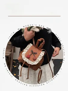 Détail du mini sac à dos vintage marron avec bordure en dentelle blanche et cerises