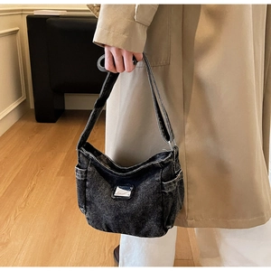 Vue détaillée du sac bandoulière en denim gris foncé délavé avec une plaque métallique