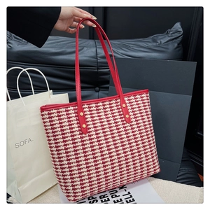 Detail of red and white houndstooth knit tote bag featuring leather handles and gold rivets