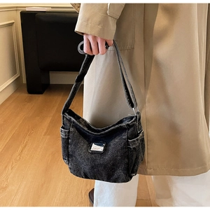 Close-up of vintage black denim tote bag with metal plaque and adjustable strap detail
