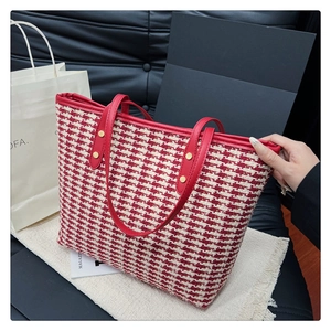 Detailed close-up of red and white houndstooth tweed tote bag with leather handles