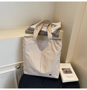 Détail du sac cabas beige imperméable avec couture verticale et logo métallique