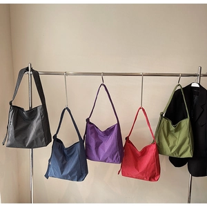 Detail view of large capacity plaid tote bags in five various colors on a hanger