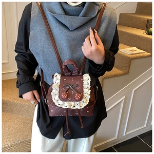 Détail d'un sac à dos vintage marron à fleurs avec dentelle et décor cerise