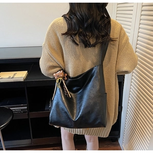 Détail du grand sac hobo en cuir souple noir avec une breloque d'ours marron mignonne
