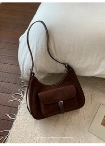 Detail of dark brown suede shoulder bag with magnetic flap pocket and silver buckle