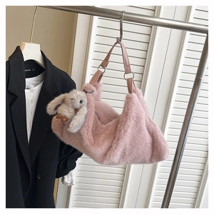 Dettaglio di una borsa a tracolla in peluche rosa con un simpatico ciondolo a coniglio