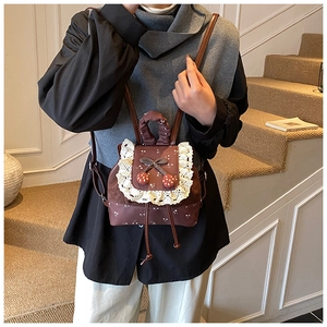 Détail du mini sac à dos vintage avec broderie dentelle, nœud et pendentif fraise