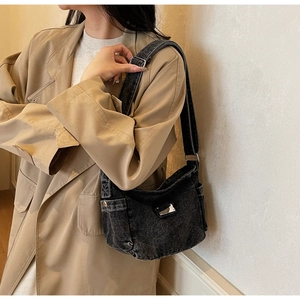 Détail du sac en jean noir délavé avec boucle ajustable et texture métallique vintage