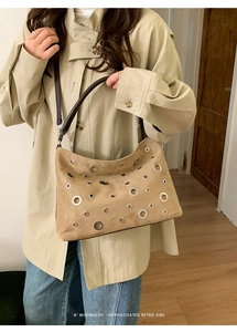 Detail of khaki hobo bag with silver metallic eyelets and dark brown leather handle
