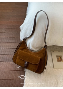 Detail view of brown suede retro crescent bag with buckle on cozy textured background
