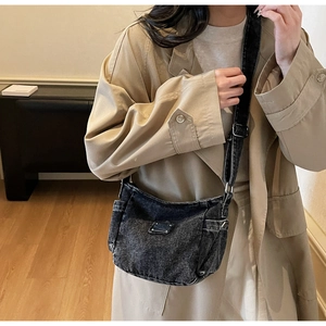 Close-up of washed charcoal denim shoulder bag with silver metal buckle and utility pocket