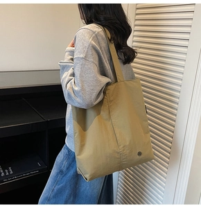 Détail d'un grand sac cabas kaki vert montrant la texture en nylon et la boucle décorative ronde