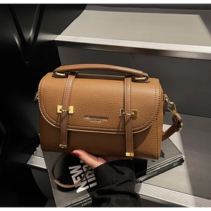 Detail shot of brown lychee grain leather handbag with stylish metal buckle and top handle