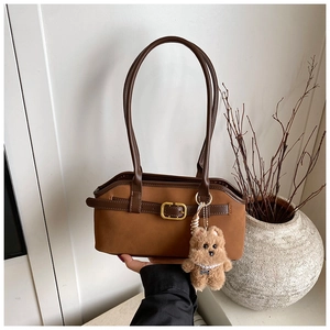 Nahaufnahme der braunen Vintage-Matt-Schultertasche mit Metallschnalle und Bärenanhänger