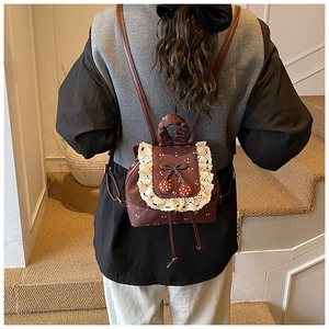 Vue détaillée du mini sac à dos marron vintage avec bordure dentelle et charms cerise