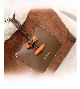 Detail of brown suede tote bag with faux shearling trim and stylish toggle buttons