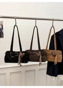 Three leather shoulder bags with heart pendant and buckle detail on display stand